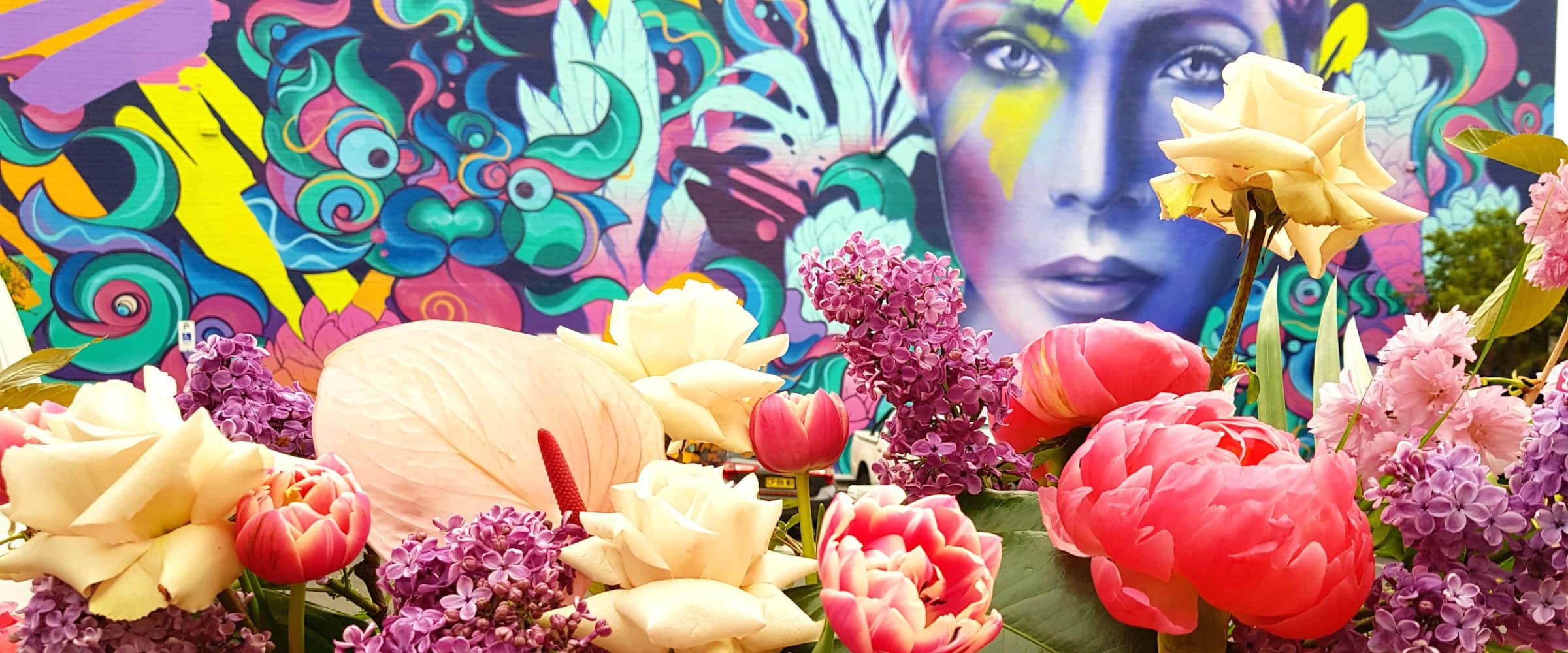 Fresh flowers in front of a colourful Newtown street mural